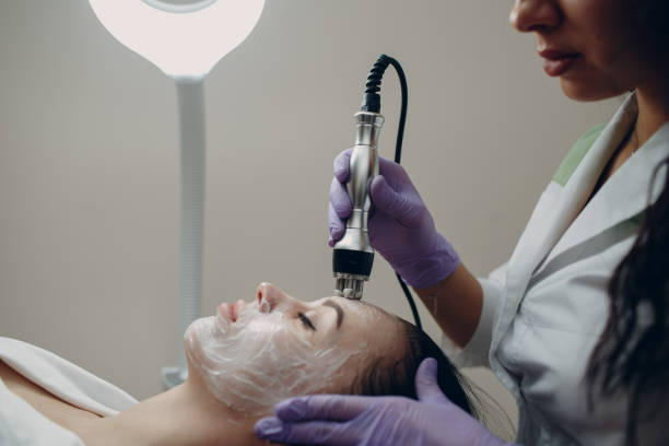 jeune femme recevant un massage facial électrique de levage rf au spa de beauté avec équipement d’électroporation. - head massage audio photos et images de collection