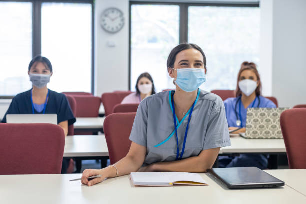 The future faces of our medical industry Muti-ethnic group shot of trainee medical students. The students are all adhering to social distancing rules and seated apart. Shot focused on a caucasian woman seated in the front row who is smiling and listening to the lecturer. New normal concept. Modern classroom setting. university students australia stock pictures, royalty-free photos & images