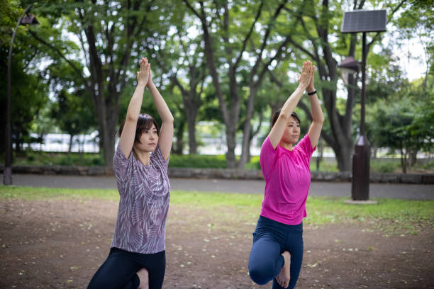 istock Female athletes doing yoga in public park 1323776608
