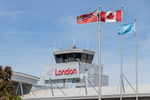 London International Airport (YXU) Air Traffic Control Tower above the airport's terminal with a text sign that reads London and the Canadian and Ontario flags waving in front.