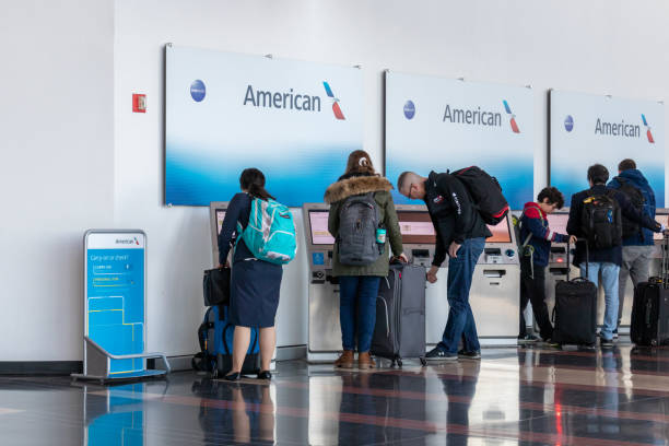 People are seen using self-serve check-in kiosks for American Airlines. stock photo