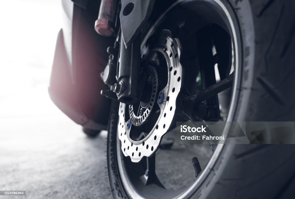 Closeup disc brake of a scooter. Aluminum alloy wheel of motorcycle. Steel rims. Mag wheels of motorbike. Performance wheel and tire of motorcycle. Chrome disc brake and abs. motorbike accessory. Motorcycle Stock Photo