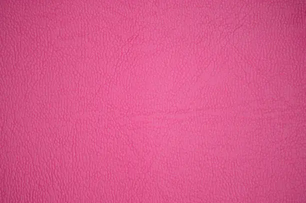 High-quality genuine leather with a small rough pattern, artificially dyed in a dark pink color. Background, pattern, texture.