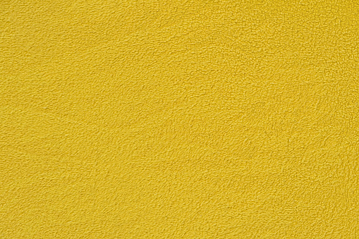 Yellow background with a textural surface. Yellow fabric, fleece.