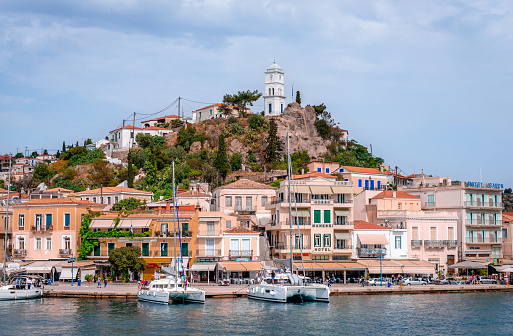 Poros, Greece - April 29 2018 - View of the waterfront and the village. The iconic clock tower dominates the skyline.