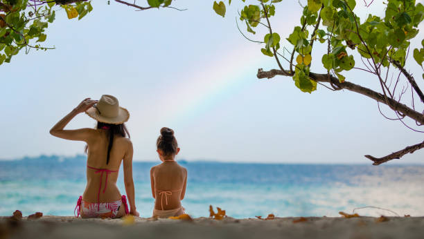 Mother and daughter watching the rainbow on the beach