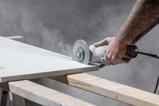 Man cutting kitchen countertop with saw with tattoos