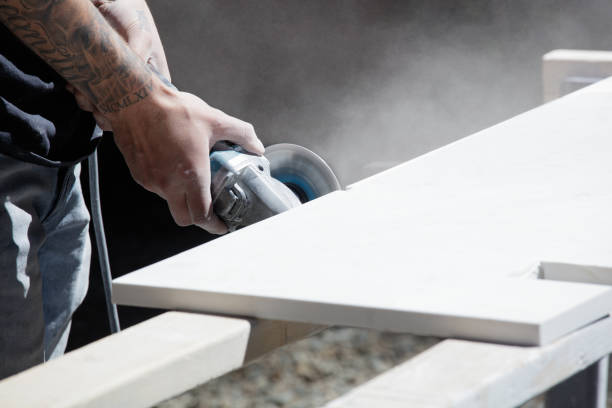 istock Man with tattoo cutting kitchen countertop with saw 1323805986