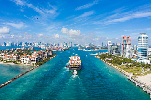 Large Container Ship Entering Harbor and Miami City on Sunny Day, USA. Aerial View