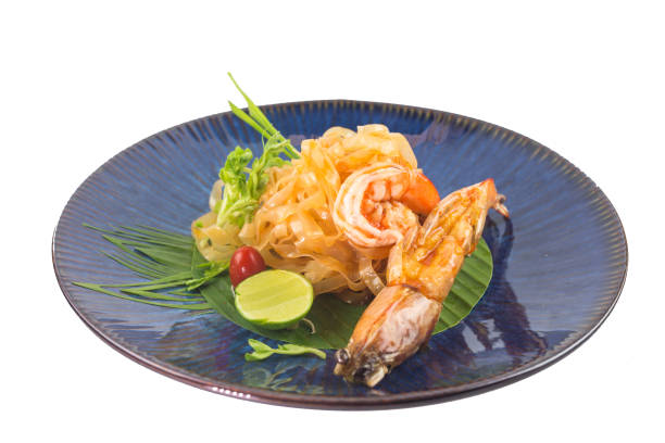 istock Fried noodle Thai style with prawns or Pad Thai in blue plate on white background 1323812653