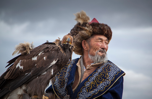 Bayan Ulgii, Mongolia, October 4th, 2015: Eagle hunter riding a horse  with his Altai Golden Eagle