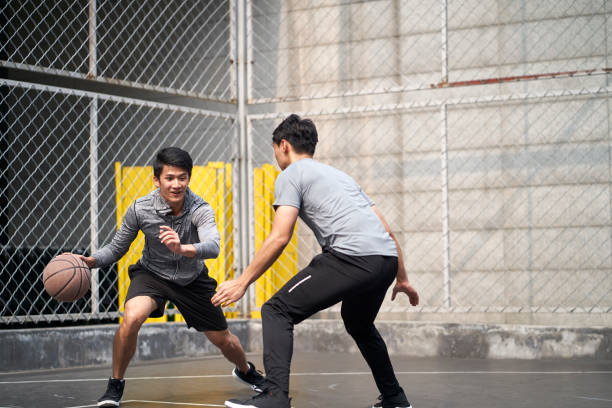 istock two young asian men playing one-on-one basketball 1323825052
