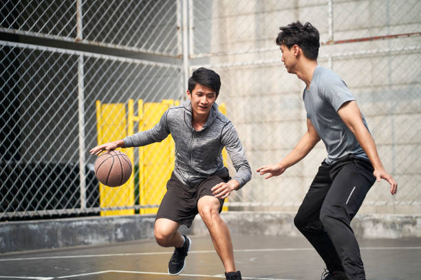 istock two young asian men playing one-on-one basketball 1323825078