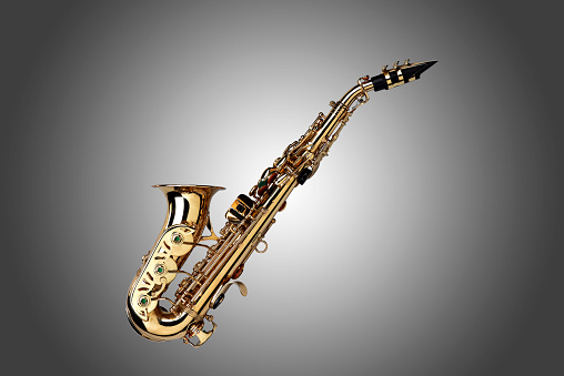 Golden colored saxophone on grey gradient background