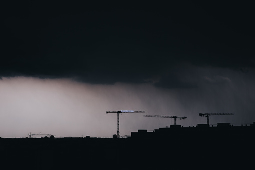 Dark construction cityscape in storm Strasbourg France. Clouds, rain and rooftop silhouette. Urbanization overpopulation and industrialization concept