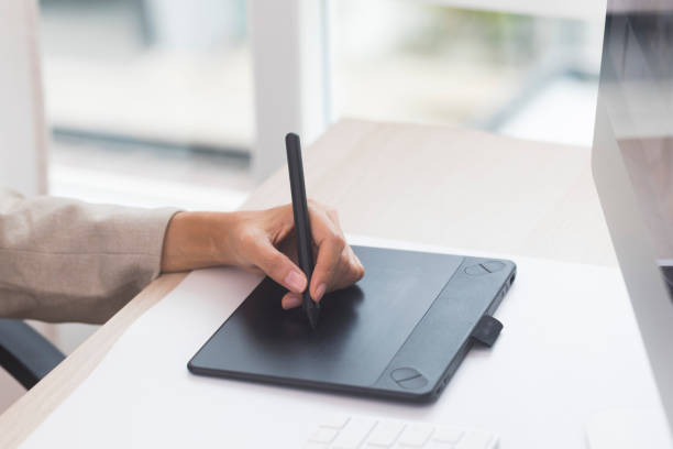 istock Designer's hand holding pen and working with graphics tablet. 1323829594