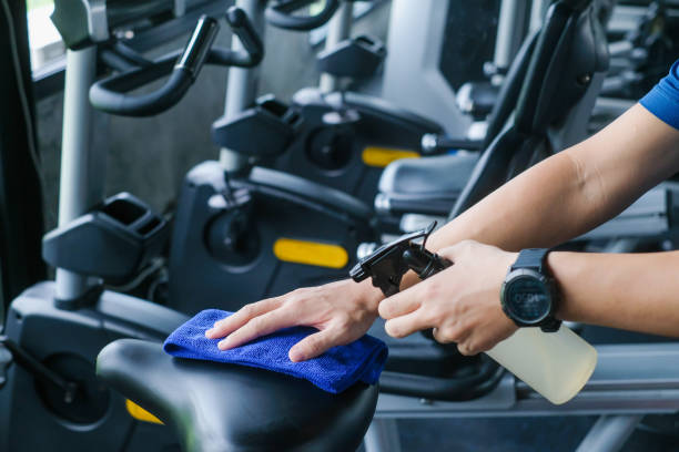 partial view ofm an cleaning sports equipment in gym on blurred foreground stock photo