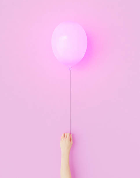 istock hand holding a pink balloon 1323830885