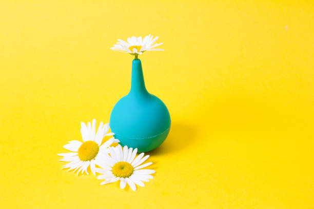 green small enema and chamomile on yellow background
