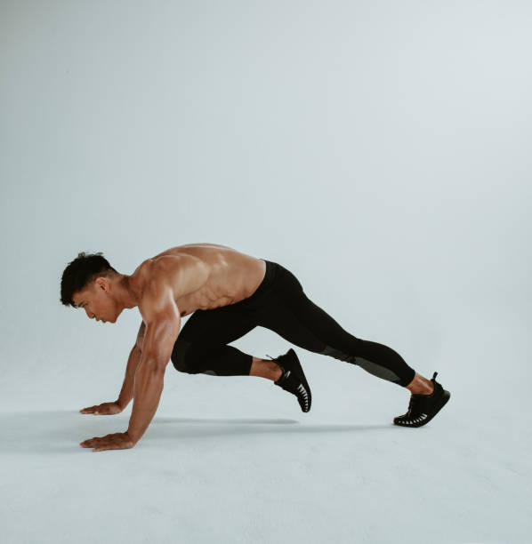 Mountain climbers cardio exercise Strong man doing mountain climbers cardio exercise. Fit young man doing cross body workout over white background. gym men africa muscular build stock pictures, royalty-free photos & images