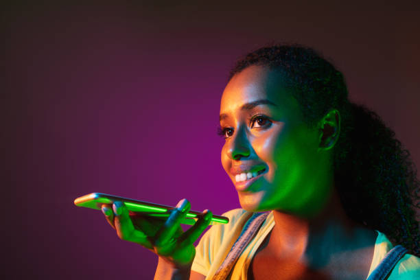 istock Recording voice message. Woman's modern portrait on gradient orange studio background in neon. 1323834450
