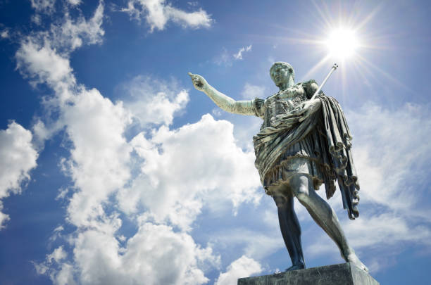 Bronze statue of the Roman Emperor Caesar Octvianus Augustus, Rome, Via dei Fori Imperiali, Italy. tatue with blue sky, clouds and sun background. bronze statue stock pictures, royalty-free photos & images