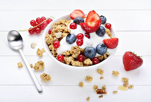 Tasty breakfast with crunchy granola, fresh berries and white yogurt, close-up.