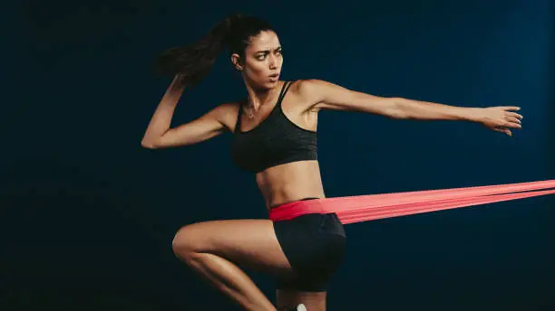 Fitness woman working out with resistance band. Sportswoman doing stretching exercises with elastic band.