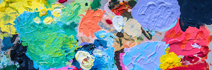 Close up view of abstract oil painting with visible paintbrush.