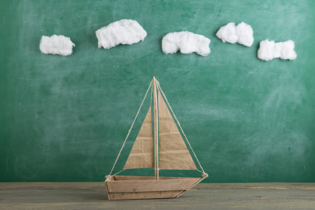istock Education is a journey concept, toy boat under cotton clouds on the chalkboard background, inspiration for a fairy tale 1323846721