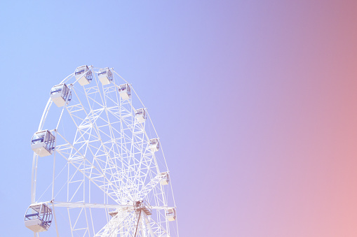 Retro colorful ferris wheel of the amusement park on the background of the rainbow sky.