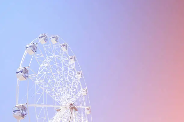 Photo of Retro colorful ferris wheel of the amusement park on the background of the rainbow sky.