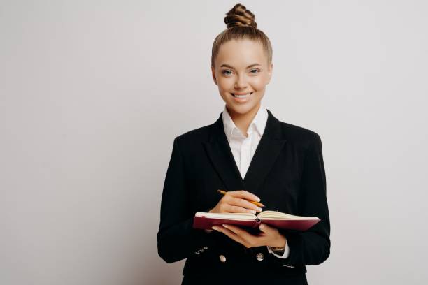 istock Business woman in dark suit writing in note book 1323849270
