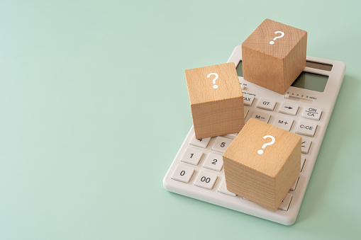COST; Wooden blocks with question mark text of concept and a calculator.