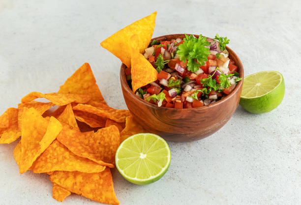 istock Mexican appetizer Pico de Gallo in a bowl and ingredients on the table. 1323854021
