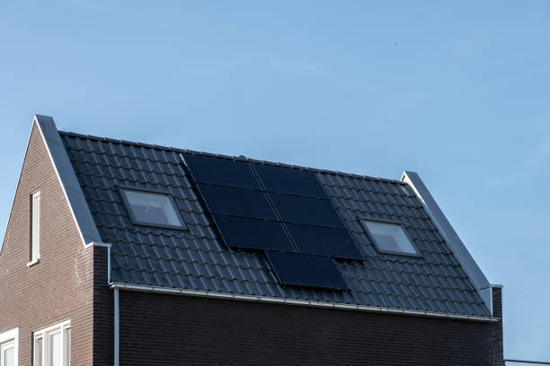 日当たりの良い空に対して屋根に取り付けられたソーラーパネルを備えた新築住宅黒いソーラーパネルで新しい建物を閉じます。ゾンネパネン、ゾンネエナギー、翻訳:ソーラーパネル、太陽 - energie ストックフォトと画像