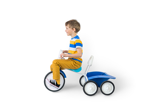 The boy rides a tricycle with a trunk for transporting. Isolated on white.