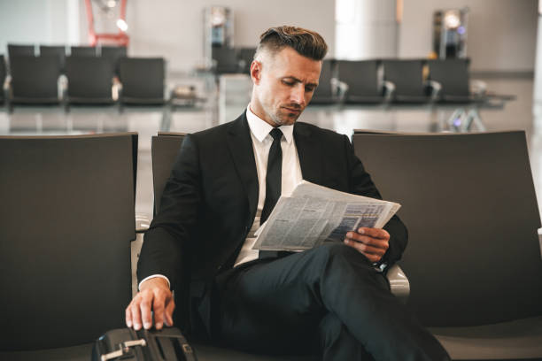 hombre de negocios confiado leyendo periódico - airport newspaper travel business travel fotografías e imágenes de stock