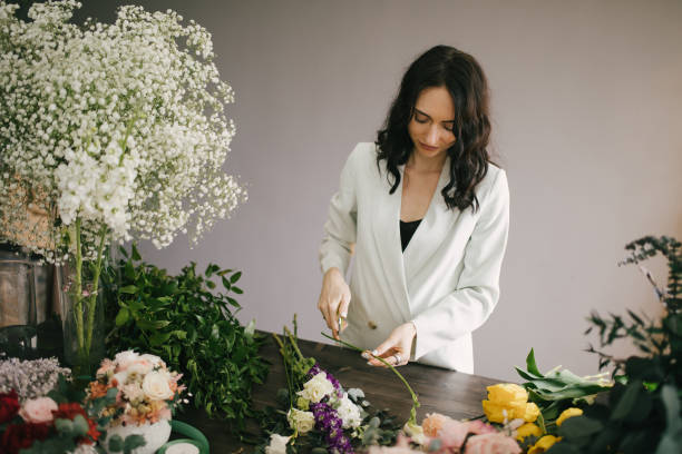 istock Young woman florist working in her flower studio, making beautiful bouquet using fresh plants and flowers. 1323857315