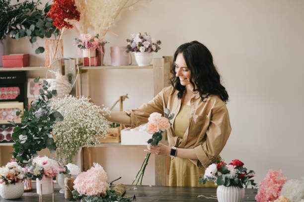 istock Young woman florist working in her flower studio, making beautiful bouquet using fresh plants and flowers. 1323857352