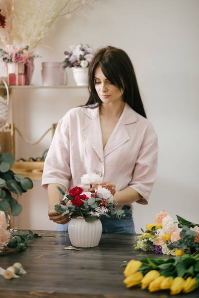 istock Young woman florist working in her flower studio, making beautiful bouquet using fresh plants and flowers. 1323857360