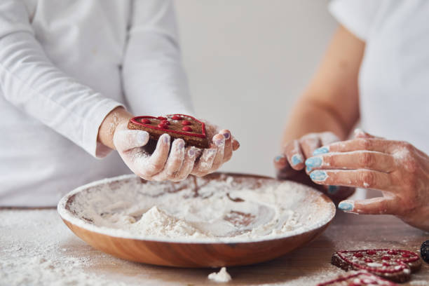 крупным планом вид женщины с внучкой приготовления пищи с мукой на кухне - grandmother domestic life cooking domestic kitchen стоковые фото и изображения