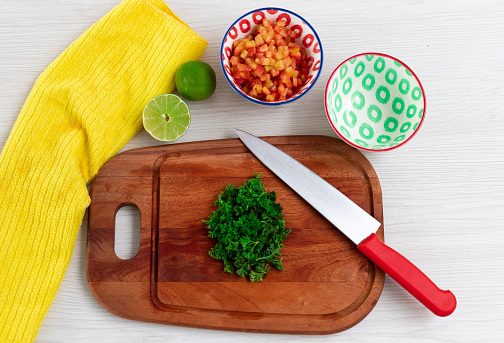 Vegetables with cutting board, tomato concasse, cilantro, lemon, bowls and yellow kitchen towel. Healthy food