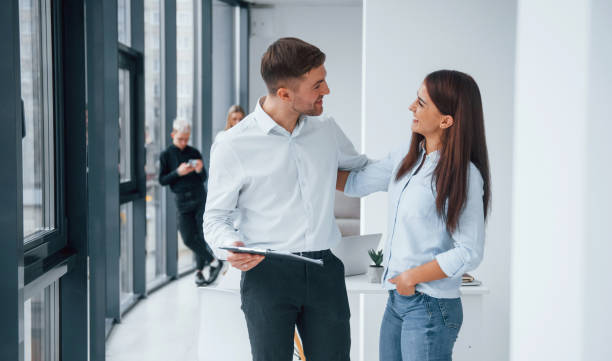 istock Woman and man talking about documents in front of young successful team that working and communicating together indoors in office 1323865581