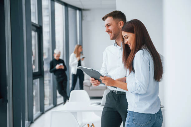 istock Woman and man talking about documents in front of young successful team that working and communicating together indoors in office 1323865621