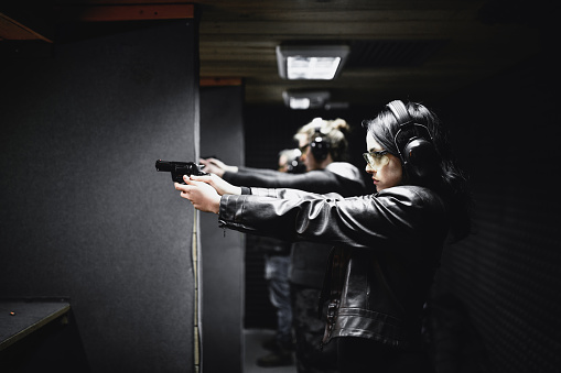 Friends Competing In Firearm Handling On Shooting Range