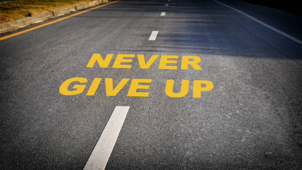 Never give up word on asphalt road surface with marking lines