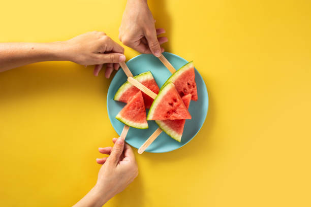 istock Hand picking up watermelon slices popsicles on blue plate 1323870123