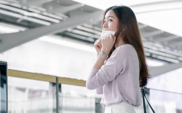 istock Woman wearing face mask and waiting for a train while standing on railway station 1323874975