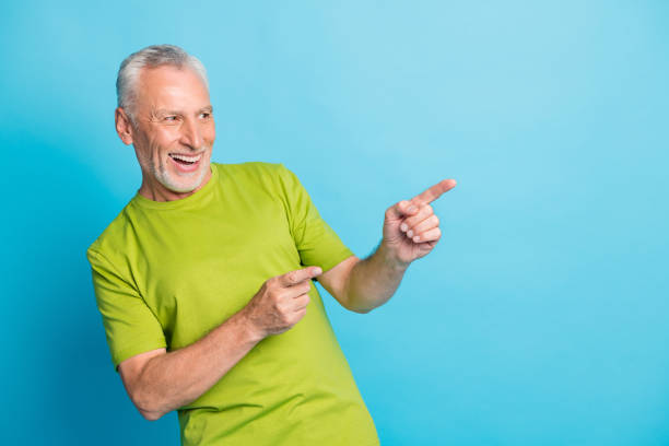 istock Portrait of aged guy look indicate fingers empty space proposition beaming smile isolated on blue color background 1323875120
